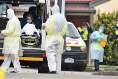 Nhân viên y tế chuyển bệnh nhân nghi mắc COVID-19 lên xe cứu thương tại bang Victoria, Australia. (Ảnh: AFP/TTXVN)