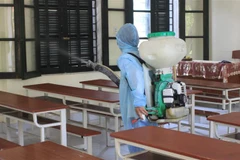 Cán bộ y tế phường phun khử khuẩn một điểm thi tốt nghiệp THPT. (Ảnh: TTXVN phát)