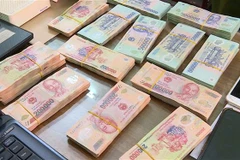 Tang vật và tiền mặt lực lượng chức năng thu giữ tại nhà các đối tượng. (Ảnh: Đinh Tuấn/TTXVN)