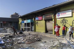 Người dân dọn dẹp đống đổ nát sau các cuộc biểu tình bạo lực tại Durban, Nam Phi. (Ảnh: AFP/TTXVN)
