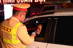 Cán bộ, chiến sỹ thuộc tổ công tác Y6/141 kiểm tra nồng độ cồn 1 tài xế ô tô tại đường Xã Đàn-Nam Đồng. (Ảnh: Phạm Kiên/TTXVN)