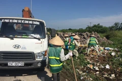Công nhân Công ty Một thành viên Môi trường đô thị Hà Nội thu dọn rác thải bị đổ trộm tại Đại lộ Thăng Long. (Ảnh: Mạnh Khánh/TTXVN)