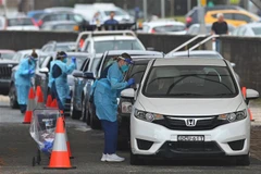 Nhân viên y tế Australia lấy mẫu dịch xét nghiệm COVID-19 cho người dân. (Ảnh: AFP/TTXVN)