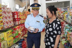 Cán bộ Quản lý thị trường hướng dẫn người tiêu dùng về các thông tin hàng hóa. (Ảnh: qltt.vn)