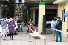 Đo thân nhiệt trước khi tiêm vaccine. (Ảnh: TTXVN)