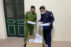 Đội Quản lý thị trường số 5 phối hợp với Công an quận Hai Bà Trưng kiểm tra số kit test COVID-19 vừa thu giữ. (Ảnh: PV/Vietnam+)