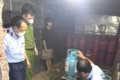 Lực lượng chức năng tiến hành kiểm tra hàng hóa có dấu hiệu vi phạm về kinh doanh khí hóa lỏng. (Ảnh: PV/Vietnam+)