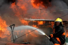 Nhân viên cứu hỏa nỗ lực khống chế đám cháy. (Ảnh: AFP/TTXVN)