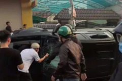 Người dân và lực lượng chức năng đập kính xe để bắt 2 đối tượng bên trong. (Nguồn: Báo Long An)