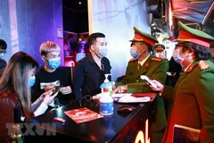 Lực lượng Công an quận Hoàn Kiếm kiểm tra thiết bị đo thân nhiệt tại vũ trường The Bunker, nơi tập trung đông người tại phố Mã Mây, quận Hoàn Kiếm. (Ảnh: Doãn Tấn/TTXVN) 