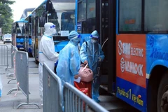 Người dân ngõ 328 Nguyễn Trãi, phường Thanh Xuân Trung lên xe di chuyển đến khu cách ly tập trung. (Ảnh: Tuấn Anh/TTXVN)