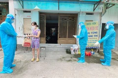 Nhân viên y tế trạm y tế lưu động phường 25, quận Bình Thạnh phát túi thuốc cho F0 điều trị tại nhà. (Ảnh: Đinh Hằng/TTXVN)