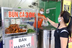Từ 6h20, một quán bún cá trên phố Mai Hắc Đế đã có khách mua mang về. (Ảnh: Hoàng Hiếu/TTXVN)