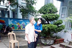 Giúp đỡ người dân đến tiêm vaccine tại điểm trường THCS Lương Khánh Thiện, Hà Nam. (Ảnh: Đại Nghĩa/TTXVN)