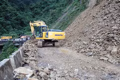Phương tiện máy móc triển khai san gạt đất, đá sạt lở trên Quốc lộ 8A. (Ảnh: TTXVN)