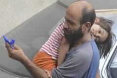 Anh Abdul Halim al-Attar bế con nhỏ đi bán bút. (Nguồn: metro.co.uk)