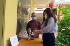 Người dân rửa tay sát khuẩn trước khi vào lễ chùa. (Ảnh: TTXVN)