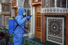 Nhân viên y tế phun thuốc khử trùng nhằm ngăn chặn sự lây lan của dịch COVID-19 tại một nhà thờ ở Amman, Jordan. (Ảnh: AFP/TTXVN)