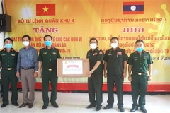 Đại diện lãnh đạo Bộ Tư lệnh Quân khu 4 (bên trái) trao tặng vật tư y tế cho đại diện quân đội Lào. (Ảnh: TTXVN)