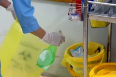 Nhân viên y tế Trung tâm y tế huyện Bình Xuyên xịt dung dịch sát khuẩn vào thùng lưu chứa chất thải trước khi để vào nơi quy định. (Ảnh: Hoàng Hùng/TTXVN)