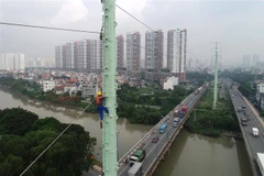 Công nhân Tổng Công ty Điện lực Thành phố Hồ Chí Minh thi công trồng trụ điện trên đường Đồng Văn Cống. (Ảnh: TTXVN)