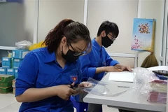Đoàn thanh niên phường Cống Vị tự làm kính chắn giọt bắn trang bị cho các lực lượng tham gia phòng, chống dịch COVID-19 trên địa bàn. (Ảnh: TTXVN)