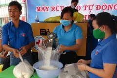 Người dân nhận hỗ trợ từ máy rút gạo tự động. (Ảnh: K GỬIH/TTXVN)