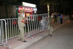 Lực lượng chức năng tiến hành tháo dỡ rào chắn phong tỏa tại một tuyến phố. (Ảnh: Mạnh Minh/TTXVN)