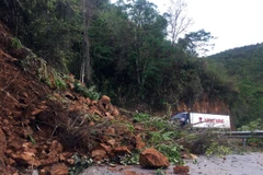 Đất đá bị cuốn trôi trên mặt đường gây khó khăn cho các phương tiện tham gia giao thông tại km 109 trên Quốc lộ 279. (Ảnh: Phan Tuấn Anh/TTXVN)