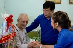 Anh Lê Quốc Phong, Ủy viên dự khuyết Trung ương Đảng, Bí thư thứ nhất Trung ương Đoàn tặng quà cho cựu chiến binh Đoàn Hà. (Ảnh: Hồng Giang/TTXVN)