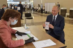 Tổng thống Nga Vladimir Putin (phải) làm thủ tục tại điểm bỏ phiếu trưng cầu dân ý về sửa đổi Hiến pháp ở Moskva ngày 1/7/2020. (Ảnh: AFP/TTXVN)