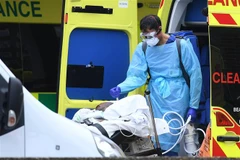 Nhân viên y tế chuyển bệnh nhân mắc COVID-19 từ xe cứu thương vào một bệnh viện ở London, Anh ngày 1/4/2020. (Ảnh: AFP/TTXVN)