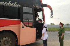 Lực lượng chức năng tỉnh Vĩnh Phúc thực hiện đo thân nhiệt và khử khuẩn đối với các loại phương tiện trên tuyến đường Quốc lộ 2. (Ảnh: Nguyễn Thảo/TTXVN)