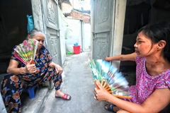 Nhiều bệnh nhân ở xóm chạy thận Lê Thanh Nghị chọn cách ra cửa ngồi quạt tay để chống chọi với cái nóng như thiêu đốt trong những căn phòng trọ chật hẹp. (Ảnh: Thành Đạt/TTXVN)
