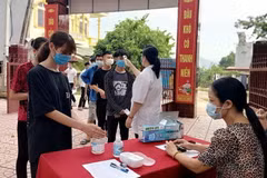 Thí sinh được đo thân nhiệt, rửa tay sát khuẩn trước khi vào làm thủ tục dự thi. (Ảnh: Xuân Thỏa/TTXVN)