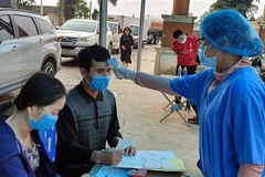 Cán bộ y tế tiến hành đo thân nhiệt và kê khai y tế tại chốt kiểm soát COVID-19 cầu Vàng Chua, thị xã Đông Triều, tỉnh Quảng Ninh. (Ảnh: Đức Hiếu/TTXVN)
