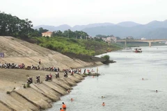 Người dân dựng xe la liệt bên bờ sông Đà để xuống tắm sông, phớt lờ cảnh báo nguy hiểm. (Ảnh: Trọng Đạt/TTXVN)