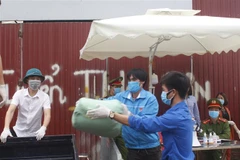 Lực lượng liên ngành khẩn trương vận chuyển hàng hóa đưa vào trong thôn Hạ Lôi. (Ảnh: Nguyễn Thắng/TTXVN)