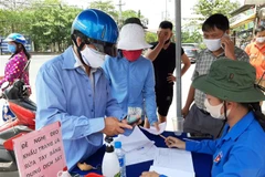 Người dân tự nguyện đến hỗ trợ tiền, gạo. (Ảnh: Đức Hạnh/TTXVN)