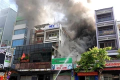 Lực lượng chức năng có mặt tại hiện trường để khống chế đám cháy. (Ảnh: TTXVN)