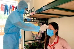 Cán bộ tổ công tác đo thân nhiệt cho người dân trong khu cách ly trường quân sự Sơn Tây. (Ảnh: TTXVN)