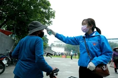 Kiểm tra thân nhiệt cho người dân. (Nguồn: TTXVN)