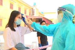 Bác sỹ kiểm tra thân nhiệt cho công dân. (Ảnh: Đinh Tuấn/TTXVN)