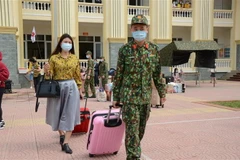 Các chiến sỹ giúp những người được cách ly vận chuyển hành lý. (Ảnh: TTXVN)