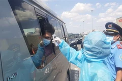 Nhân viên y tế đo thân nhiệt người ra vào Thành phố Hồ Chí Minh tại chốt kiểm dịch. (Ảnh: Đinh Hằng/TTXVN)