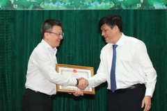 Thứ trưởng Bộ Y tế Nguyễn Thanh Long trao Bằng khen cho nhà báo Lê Quốc Minh, Phó Tổng Giám đốc TTXVN vì thành tích xuất sắc trong công tác thông tin, tuyên truyền về phòng, chống dịch COVID-19. (Ảnh: Thành Đạt/TTXVN)