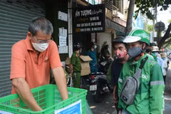 Nhóm thiện nguyện 'Quán cơm yên vui' phát cho người có hoàn cảnh khó khăn. (Ảnh: Văn Dũng/TTXVN)