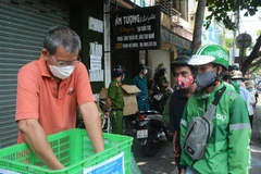 Nhóm thiện nguyện 'Quán cơm yên vui' phát cho người có hoàn cảnh khó khăn. (Ảnh: Văn Dũng/TTXVN)