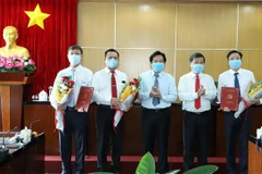 Ông Nguyễn Hoàng Thao (người thứ ba bên phải qua) - Phó Bí thư Thường trực Tỉnh ủy; ông Trần Thanh Liêm (thứ hai bên phải qua), Chủ tịch UBND tỉnh trao quyết định và tặng hoa cho các cán bộ chủ chốt được điều động, bổ nhiệm. (Ảnh: Nguyễn Văn Việt/TTXVN)
