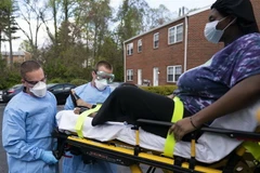 Nhân viên y tế chuyển bệnh nhân mắc COVID-19 lên xe cứu thương tại Glen Burnie, bang Maryland, Mỹ ngày 21/4/2020. (Ảnh: AFP/TTXVN)